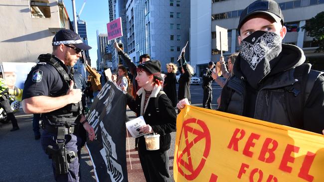 Police are seen talking to Extinction Rebellion protesters as they block morning peak hour traffic at the corner of Margaret and George Streets in Brisbane, Monday, July 15, 2019. (AAP Image/Darren England)