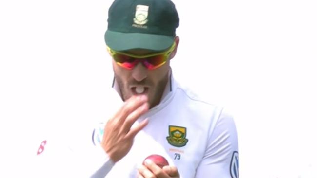 Faf du Plessis shining the ball with something in his mouth.