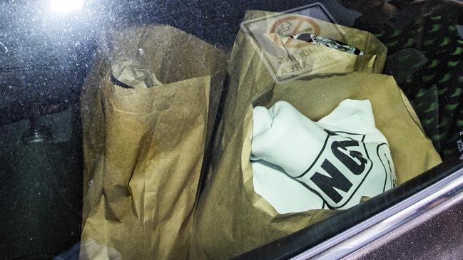 Gear in paper bags in the back of a police car.