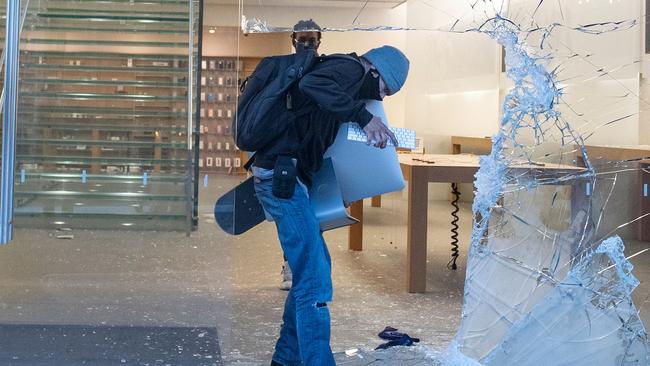 A man loots an iMac through the broken window of the Apple store in Los Angeles following a protest against the death of George Floyd. Picture: AFP