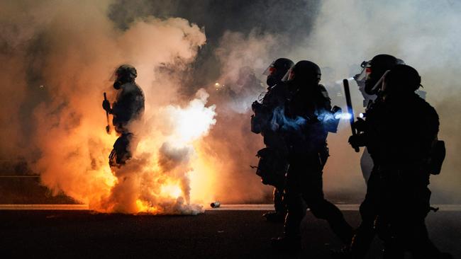 Oregon Police wearing anti-riot gear march towards protesters through tear gas smoke during the 100th day and night of protests against racism and police brutality in Portland, Oregon ub September 2020. Picture: AAP