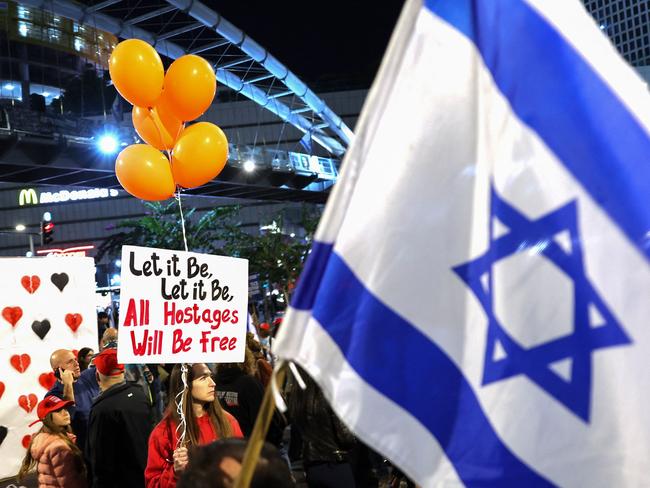 TOPSHOT - Demonstrators hold placards and wave flags during a protest in Tel Aviv on January 18, 2025, in front of the Israeli Defence Ministry, calling for the release of Israeli hostages held in Gaza since the October 7, 2023 attacks, a day before a ceasefire approved by Israel and Hamas is set to take effect. Israeli Prime Minister Benjamin Netanyahu on January 18 demanded that Hamas provide a list of names of hostages to be freed on January 19 before any prisoner swap takes place. In more than 15 months of war between Hamas Palestinian militants and Israel, there has been only one previous truce, for one week, in November 2023 that also saw a hostage-prisoner exchange. (Photo by Jack GUEZ / AFP)