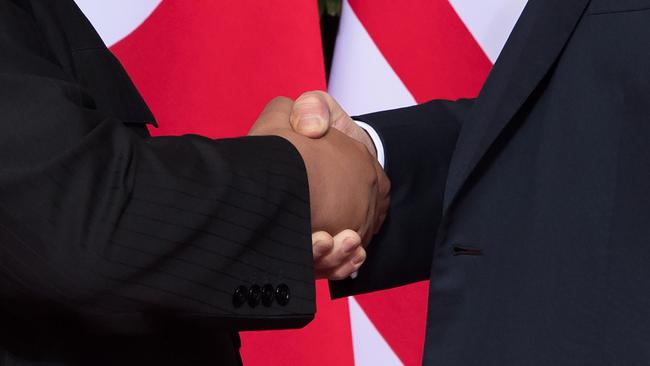 Donald Trump (R) shakes hands with North Korea's leader Kim Jong-un.