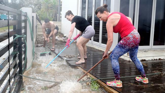 Lachlan Thompson, Karen Thompson and Louise Baker move water from the Thompsons’ back yard at Redcliffe suburb Woody Point in Queensland’s Moreton Bay region. Picture: Richard Gosling