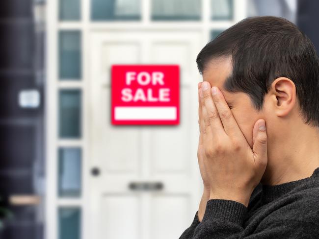 Man extremely depressed and sad about losing his house key and seeing a for sale sign, real estate concept; first home buyer generic sad, stressed