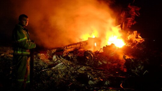 A firefighter stands as flames burst amongst the wreckag of MH17 on July 17, 2014. Picture: AFP