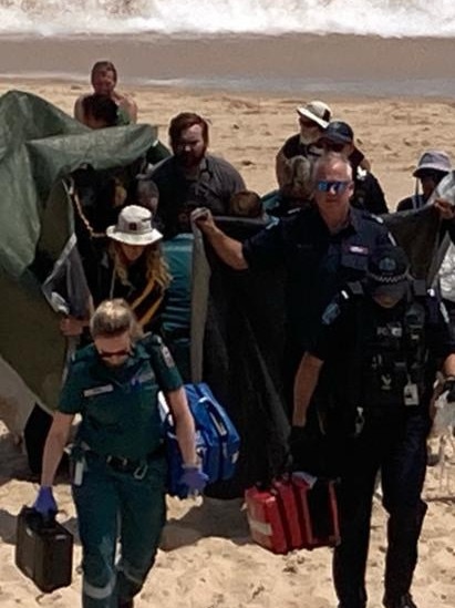 Bridgette O'Shannessy is taken from the beach at Port Noarlunga after being bitten on the face by a shark. Picture: 7NEWS