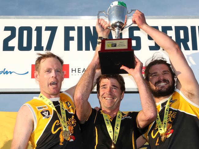 Frankston YCW coach Wayne Capp and co-captains Jie Coghlan and Kevin Lylak hold up the premiership cup. Picture: Mark Dadswell