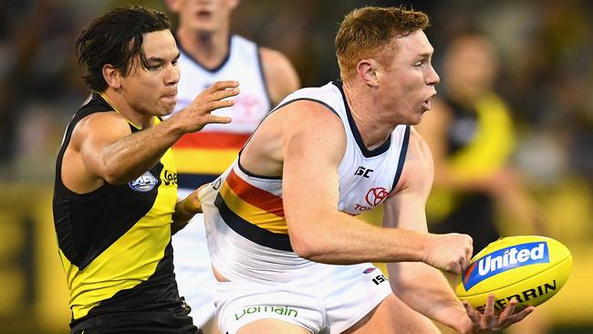 Tom Lynch of the Crows handballs while being tackled by Daniel Rioli of the Tigers. Picture: Getty Images