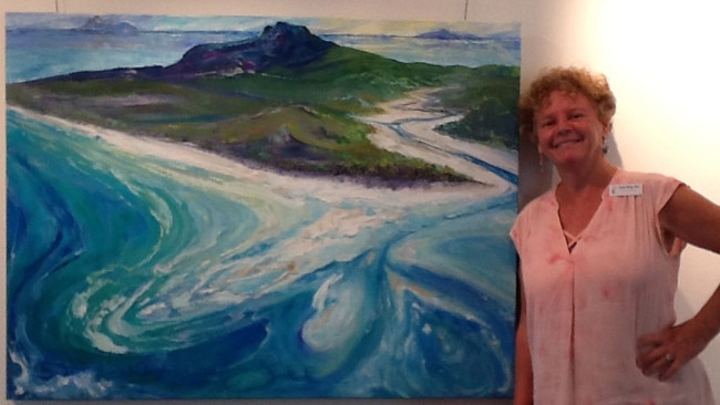 Mackay Art Society workshop co-ordinator Susan Gee with one of her paintings. The painting is of Whitehaven Beach. Picture: Contributed.