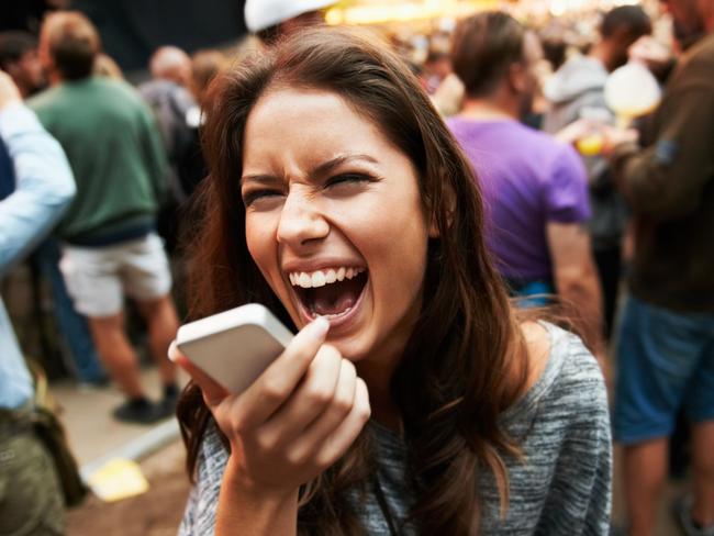 A pretty young woman shouting into her smartphone at an outdoor music festival Picture i stock image