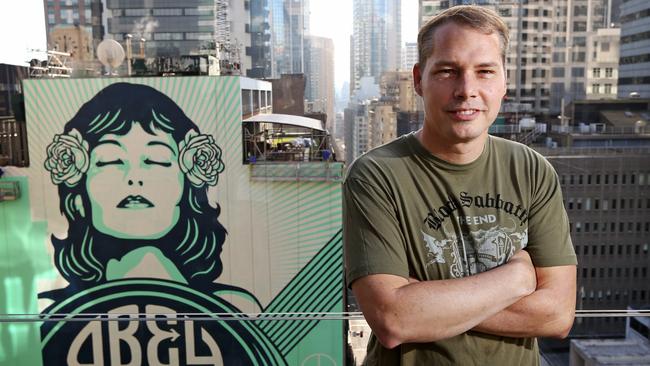 Shepard Fairey pictured with his latest mural on the side of a building in George St, Sydney. Picture: Toby Zerna