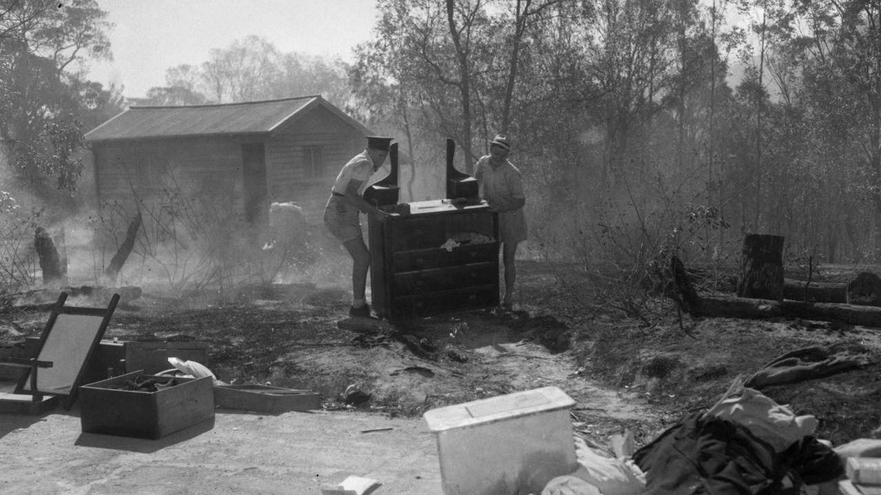 Firefighters saved this home in Indooroopilly, owned by Mr. E.L Jamieson, in 1957. Volunteers move furniture away from burning bushland. Picture: Ray Saunders