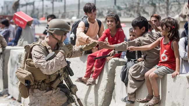 A US marine plays with children waiting to be processed during an evacuation at Hamid Karzai International Airport in Kabul last August. Picture: US Central Command via AFP