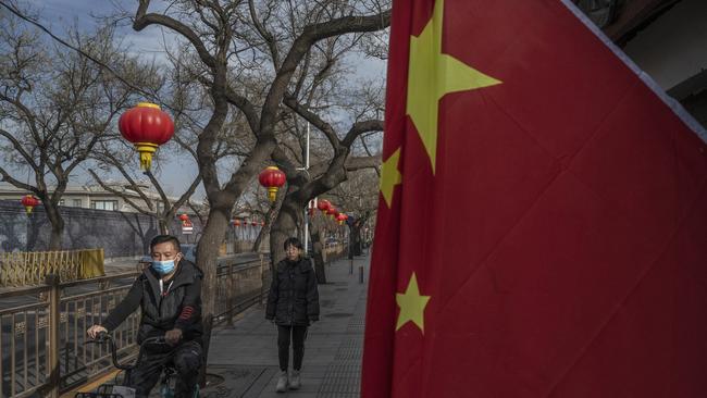 A man wears a protective mask as he rides by a flag hung for the recent Chinese New Year holiday in Beijing, China. Picture: Getty