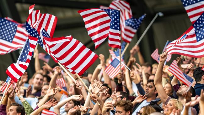 Large crowd of people at the Olympics cheering for USA and waving American flags.