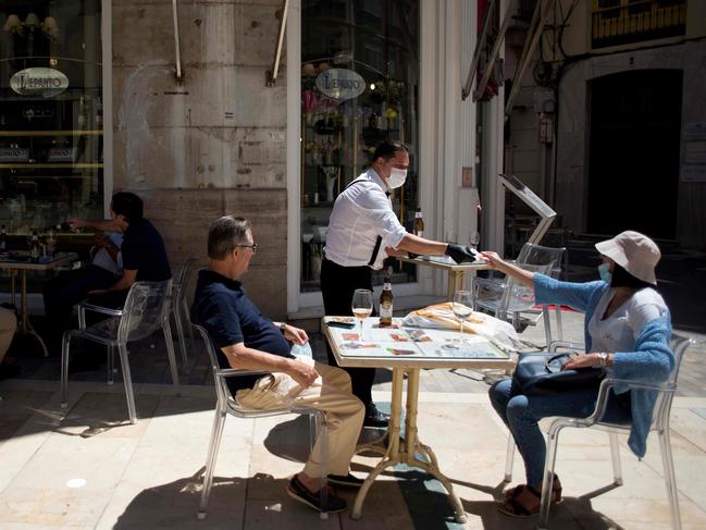 A waiter charges customers at a terrace bar in Malaga. Last week, Spain began a three-phase plan to end lockdowns for half the country by the end of June. Picture: AFP