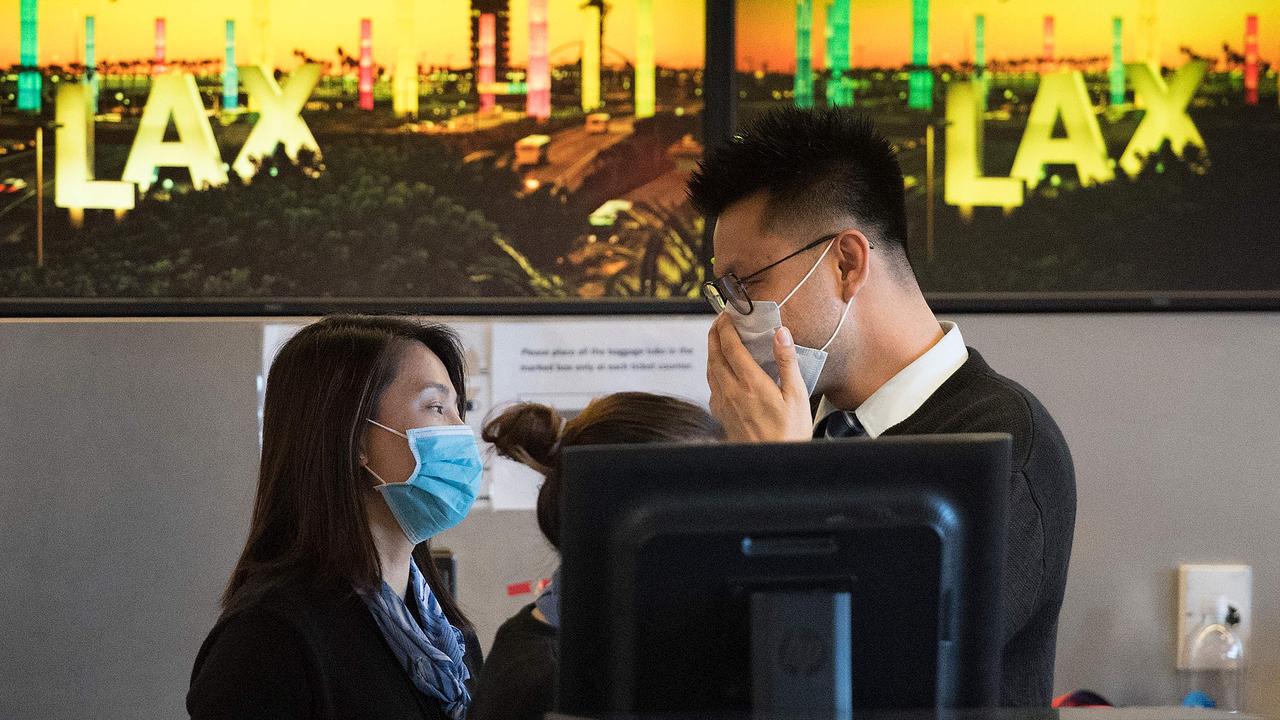 Airline check-in staff wear face masks at Los Angeles International Airport on Wednesday. Picture: Mark Ralston/AFP