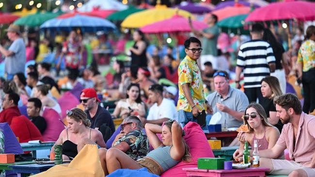 Foreign tourists relax on the Kuta Beach near Denpasar on Indonesia's resort island of Bali on November 18, 2023. (Photo by SONNY TUMBELAKA / AFP)