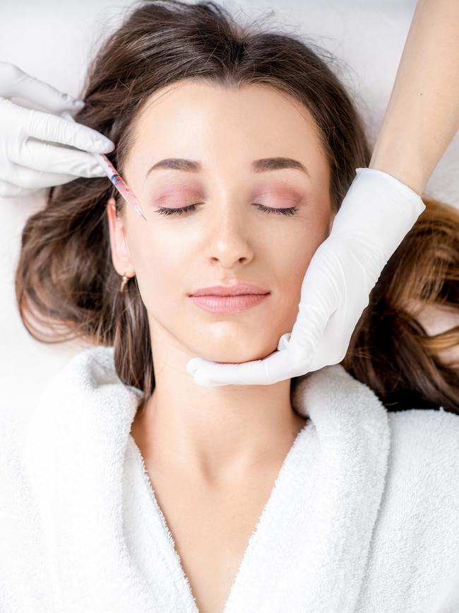 A woman receiving a botox injection in the eye zone.