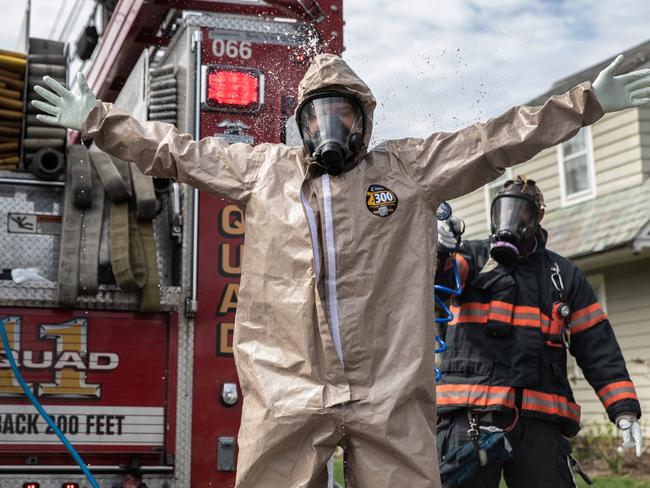 YONKERS, NEW YORK - APRIL 14: (EDITORIAL USE ONLY) Yonkers Fire Department EMTs decontaminate their full personal protective equipment (PPE), after helping carry a patient with COVID-19 symptoms out of her house for EMS transport to a hospital on April 14, 2020 in Yonkers, Westchester County, New York. Different emergency services, even within the same cities, follow varying PPE protocols in responding to COVID-19 calls. Located adjacent to New York City, Westchester County is considered part of the epicenter of the coronavirus pandemic in the United States.   John Moore/Getty Images/AFP