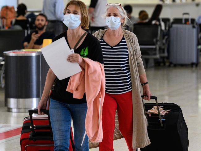 Passengers wearing protective face masks in the arrivals hall at Sydney International Airpor. Picture: James Gourley