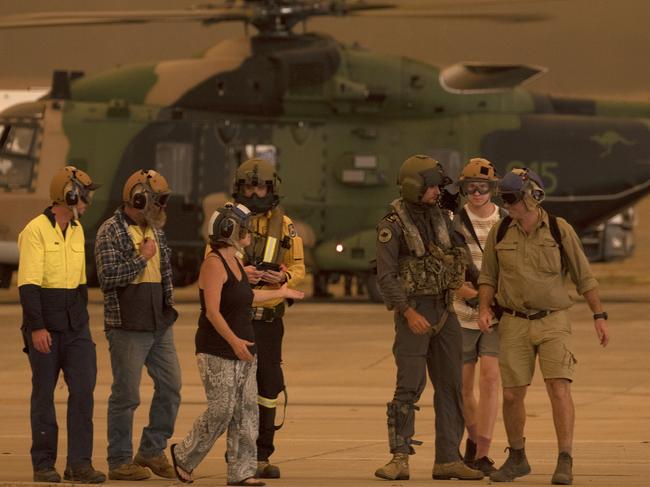 Members of the Tytherleigh family are escorted from the HMAS Albatross 808 Squadron MRH-90 Taipan by Leading Seaman Aircrewman Ben Nixon and Rural Fire Service employee Dwyane Graham after being evacuated from their property during the NSW South Coast bushfires. Picture: Supplied