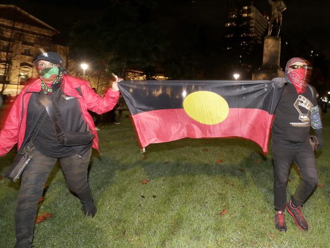 Protestors carry an Aboriginal flag as the walk past a statue of British explorer James Cook in Sydney, Friday, June 12, 2020, to support U.S. protests over the death of George Floyd. Hundreds of police disrupted plans for a Black Lives Matter rally but protest organizers have vowed that other rallies will continue around Australia over the weekend despite warnings of the pandemic risk. (AP Photo/Rick Rycroft)