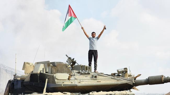 Hamas' armed wing, the Izz ad-Din al-Qassam Brigades, hold a Palestinian flag as they destroy a tank of Israeli forces in Gaza City, Gaza on October 07, 2023. Picture: Getty