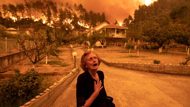 A woman leaves her home threatened by fire in the village of Gouves, on the Greek island of Evia last August. Picture: Getty Images