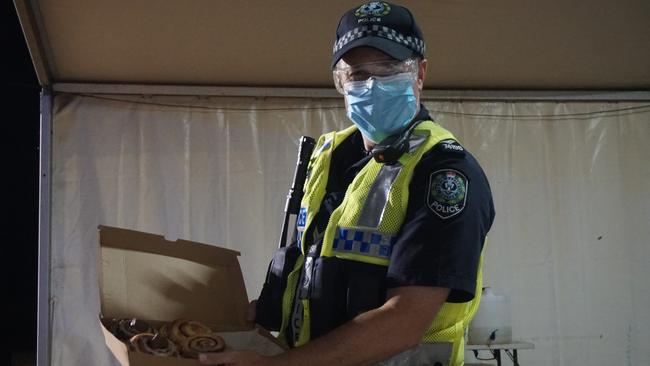 Senior constable Gary Olsen enjoys a midnight snack from Mount Gambier's famous ScRoll Queen at the Princess Highway checkpoint the South Australian border reopens to Victoria. Picture: Jessica Ball