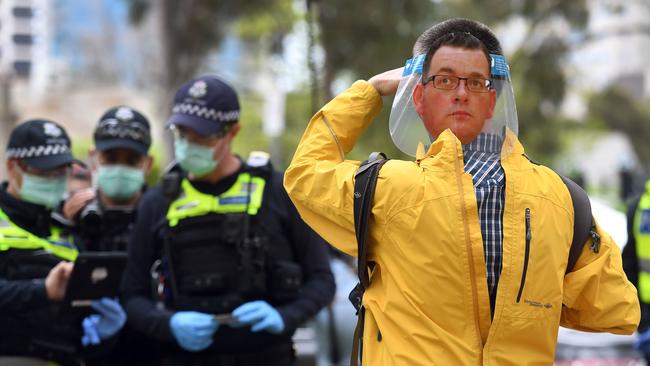 A protester wearing a face shield with an image of Victoria's Premier Daniel Andrews speaks to police during an anti-lockdown rally in Melbourne on September 12. Picture: AFP