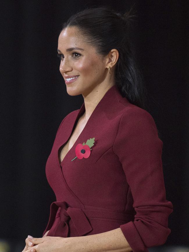 Meghan wore her hair half up, half down with a striking maroon tailored shirt and a remembrance poppy pin. Picture: AP