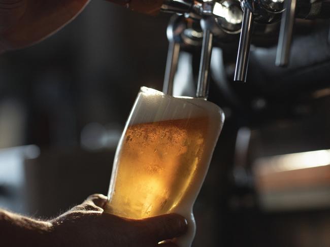 Fresh beer filling the glass directly from the tap. With extra foam spilling over glass.