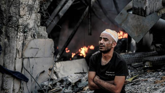 An injured man sits in front of a smouldering building in the aftermath of an Israeli strike on Gaza. Picture: AFP