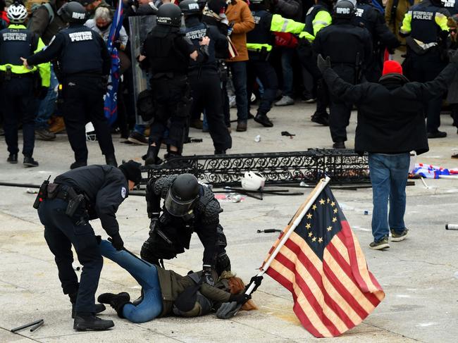 (FILES) In this file photo taken on January 6, 2021, police detain a person as supporters of US President Donald Trump riot outside the US Capitol in Washington, DC. - A day after the Senate acquitted Donald Trump in a historic second impeachment trial, America was weighing how long a shadow the former president, even with a tarnished legacy, will continue to cast -- over his party, and over the country. As much of the world watched, the Senate on February 13, 2021 voted 57-43 to convict Trump of inciting the January 6 assault on the US Capitol. It was a stinging rebuke, with seven Republicans joining all Democrats in the most bipartisan impeachment vote ever, but it fell short of the 67 votes needed for conviction. (Photo by ROBERTO SCHMIDT / AFP)