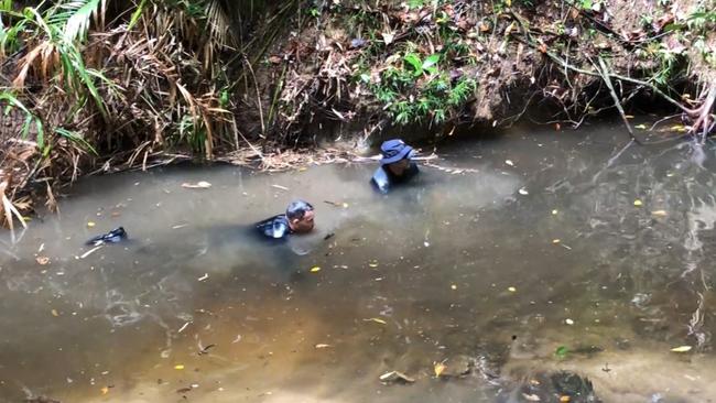 Divers crawl through a muddy creek searching for signs of the missing teen. Picture: Queensland Police Service