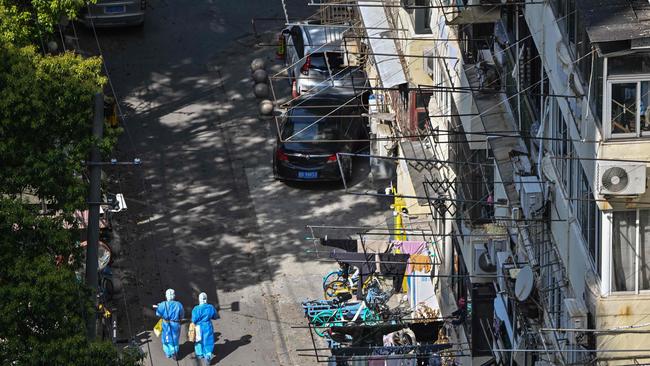 Health workers walk on a street in a neighbourhood during a COVID-19 lockdown in the Jing'an district in Shanghai. Picture: AFP.