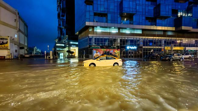 TOPSHOT - A taxi drives through a flooded street following heavy rains in Dubai early on April 17, 2024. Dubai, the Middle East's financial centre, has been paralysed by the torrential rain that caused floods across the UAE and Bahrain and left 18 dead in Oman on April 14 and 15. (Photo by Giuseppe CACACE / AFP)