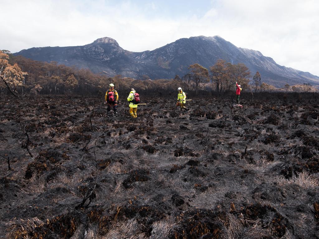 Firefighters standing in burnt buttongrass.  Gell River fire. Picture: WARREN FREY/TASMANIA FIRE SERVICE***MUST CREDIT BOTH WARREN FREY AND TASMANIA FIRE SERVICE***