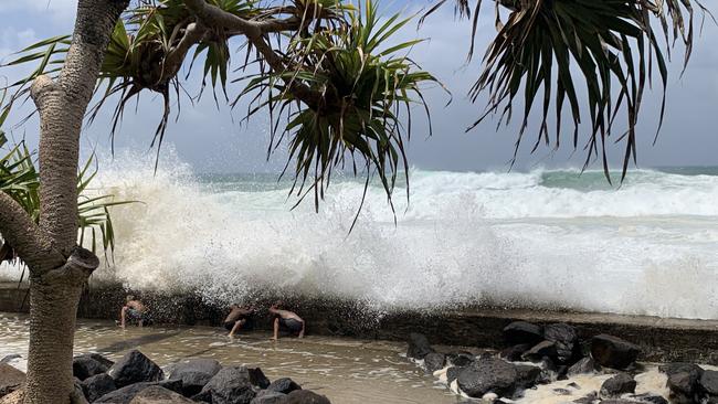 The kids were seen ducking behind a wall as large waves crashed over the rocks. Picture: Kathleen Skene