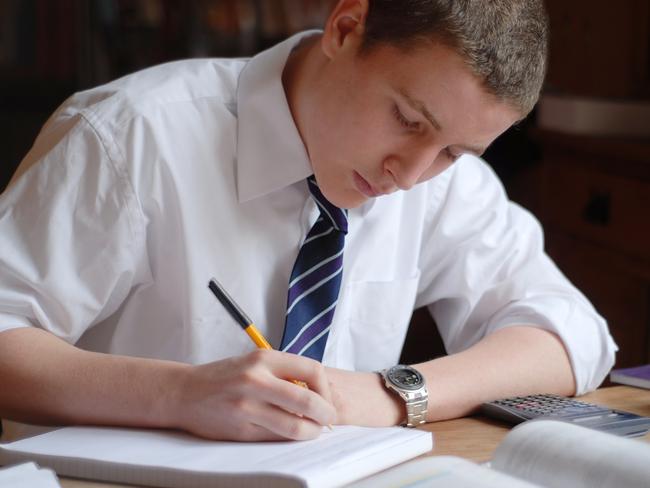 15 year old boy studying at the kitchen table.