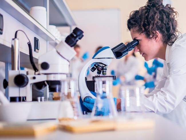 Scientist in lab doing research and using lab machines, test tubes, microscope and every laboratory equipment