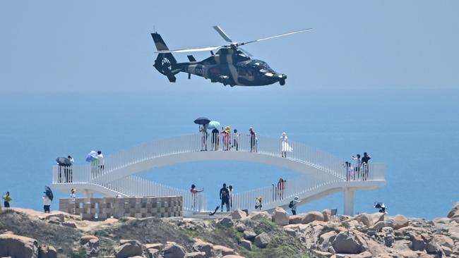 Tourists look on as a Chinese military helicopter flies past Pingtan Island, one of mainland China’s closest points from Taiwan, in Fujian province. Picture: AFP