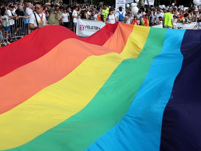 Participants display a rainbow-colored flag before taking part in the parade of the LGBTIQ (lesbian, gay, bisexual, transgender, intersex and queer) Pride in Madrid on July 1, 2023. (Photo by Pierre-Philippe MARCOU / AFP)