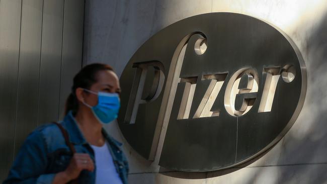 A woman wears a face mask as she walks by the Pfizer world headquarters in New York. Pfizer stock surged higher prior to the opening of Wall Street trading after the company announced its vaccine was "90 per cent effective" against Covid-19 infections. Picture: AFP