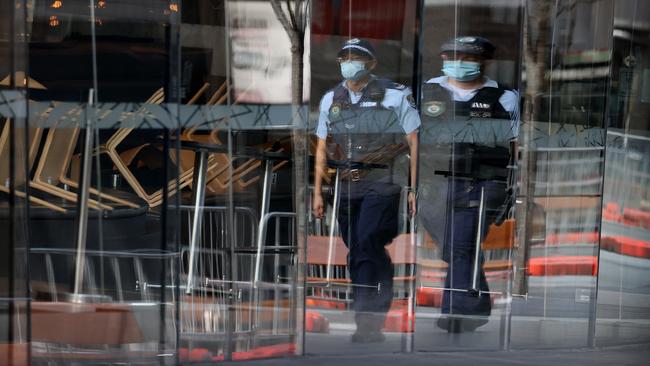 Police patrol a deserted street near a closed Sydney restaurant in August. Picture: NCA NewsWire/Dylan Coker