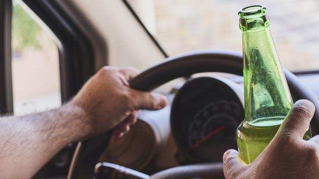 An unrecognisable man drinking beer while driving car. Concepts of driving under the influence, drunk driving or impaired driving. Drink driving generic. Picture: iSTOCK