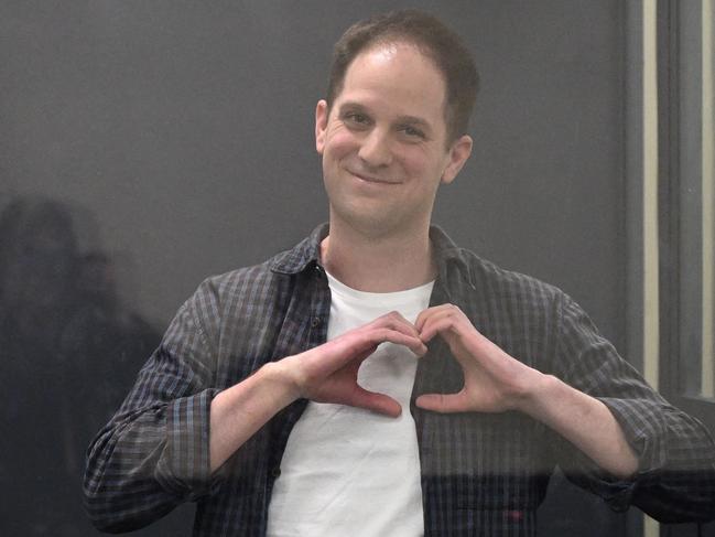 Evan Gershkovich shapes a heart with his hands inside a defendants' cage after a hearing. Picture: AFP