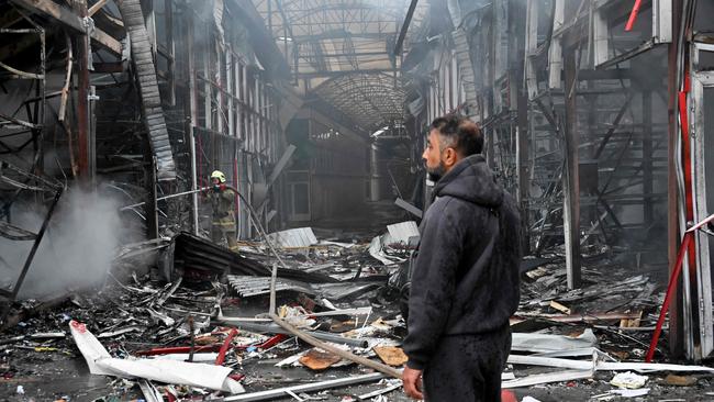 A man stands as a Ukrainian fireman finishes to put out a fire at the 